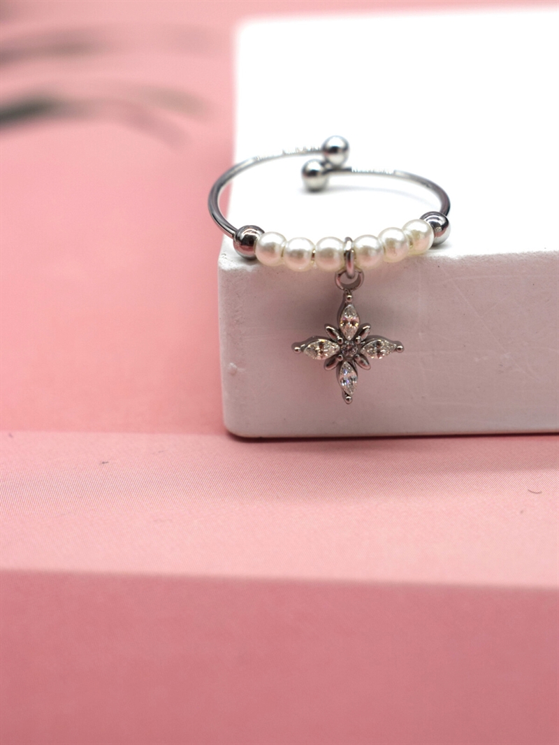 Justerbar sølvfarvet ring med hvide perler og blomst charm set forfra